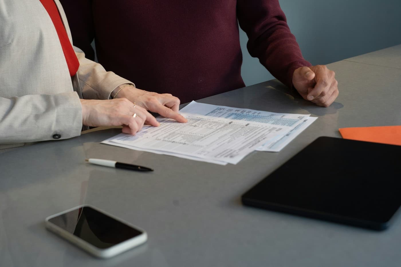 Twee personen nemen aan tafel samen de documenten van een opdracht door